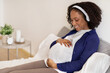 © Prostock-studio - Cheerful curly millennial black woman with big belly in wireless headphones enjoys pregnancy