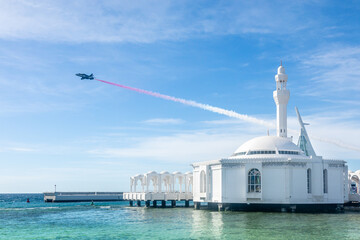 Wall Mural - Jet with smoke trace over Alrahmah floating mosque with sea in foreground, Jeddah, Saudi Arabia