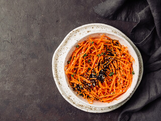 Wall Mural - Spicy sesame carrot noodles salad ready-to-eat overhead. Vegetable carrot spaghetti with black sesame and thyme. Clean eating, raw vegetarian food concept. Flat lay or top view. Copy space for text.