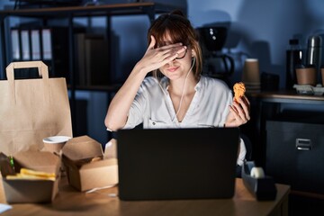 Poster - Young beautiful woman working using computer laptop and eating delivery food covering eyes with hand, looking serious and sad. sightless, hiding and rejection concept