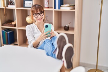 Poster - Young woman using smartphone sitting on table at home