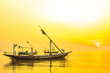 Wall Mural - Moored boats during sunrise with yellow sky in Kenjeran, Surabaya, Indonesia.