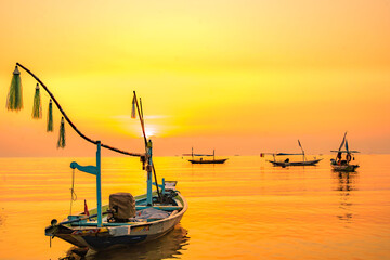 Wall Mural - Moored boats during sunrise with yellow sky in Kenjeran, Surabaya, Indonesia.