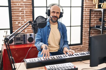 Canvas Print - Young bald man musician smiling confident playing piano at music studio