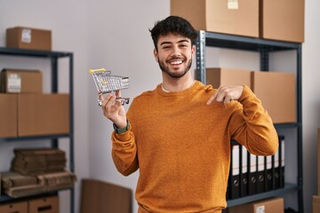 Sticker - Hispanic man with beard standing by manikin at small business holding cart pointing finger to one self smiling happy and proud