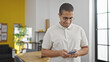 © Krakenimages.com - Young hispanic man business worker smiling confident using smartphone at office