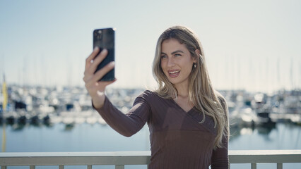 Wall Mural - Young blonde woman smiling confident making selfie by the smartphone at seaside