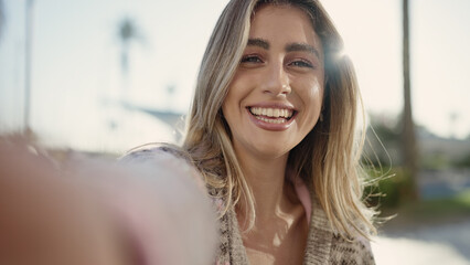 Wall Mural - Young blonde woman smiling confident making selfie by camera at street