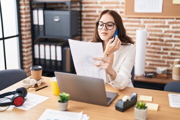 Wall Mural - Young woman business worker talking on smartphone reading document at office