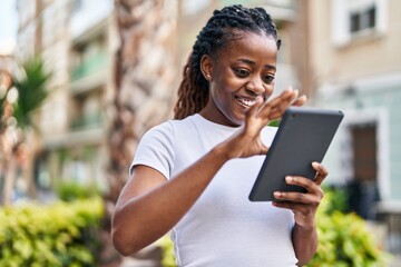 Wall Mural - African american woman smiling confident using touchpad at street