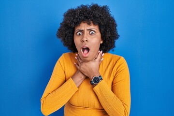 Poster - Black woman with curly hair standing over blue background shouting suffocate because painful strangle. health problem. asphyxiate and suicide concept.