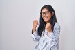 © Krakenimages.com - Young hispanic woman wearing glasses very happy and excited doing winner gesture with arms raised, smiling and screaming for success. celebration concept.
