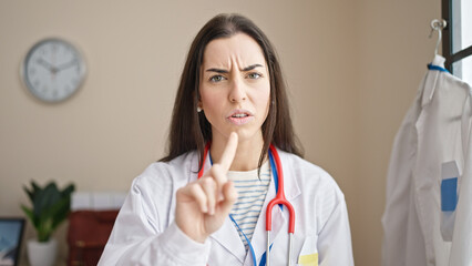 Canvas Print - Young beautiful hispanic woman doctor angry doing no gesture with finger at clinic