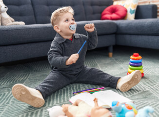 Wall Mural - Adorable caucasian boy student drawing on notebook sitting on floor at home