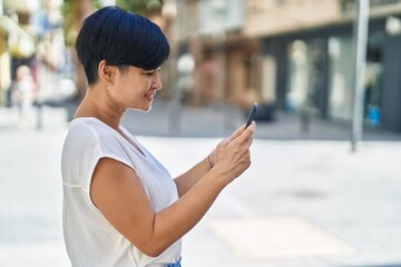 Wall Mural - Middle age chinese woman smiling confident using smartphone at street