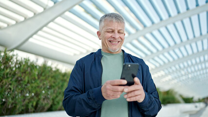 Poster - Middle age grey-haired man smiling confident using smartphone at park