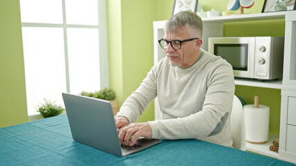 Poster - Middle age grey-haired man using laptop sitting on table at home