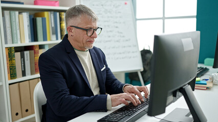 Sticker - Middle age grey-haired man teacher using computer studying at university classroom