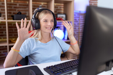 Poster - Young caucasian woman playing video games wearing headphones showing and pointing up with fingers number nine while smiling confident and happy.