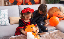 Adorable Boy And Girl Having Halloween Party Looking Pumpkin Basket At Home