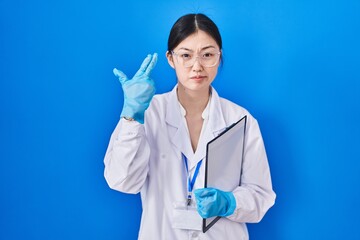 Canvas Print - Chinese young woman working at scientist laboratory shooting and killing oneself pointing hand and fingers to head like gun, suicide gesture.