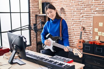 Chinese woman artist singing song playing electrical guitar at music studio