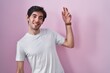 © Krakenimages.com - Young hispanic man standing over pink background dancing happy and cheerful, smiling moving casual and confident listening to music