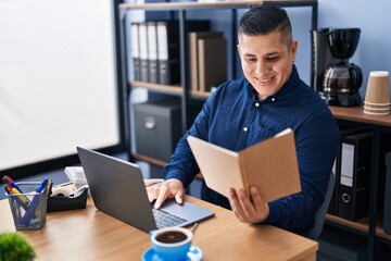 Wall Mural - Young latin man business worker using laptop reading notebook at office