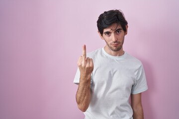 Canvas Print - Young hispanic man standing over pink background showing middle finger, impolite and rude fuck off expression