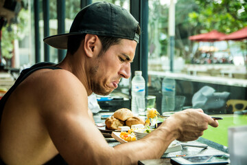 Unhappy young man eating food in a cafe