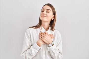 Sticker - Young caucasian woman standing over isolated background smiling with hands on chest with closed eyes and grateful gesture on face. health concept.