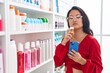 © Krakenimages.com - Young chinese woman customer using smartphone holding medicine bottle at pharmacy