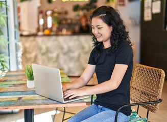Canvas Print - Young chinese woman using laptop sitting on table at restaurant