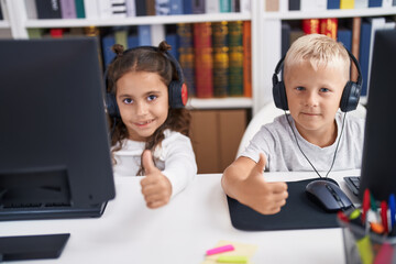 Poster - Adorable boy and girl students using computer and headphones doing thumbs up gesture at classroom