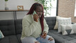 © Krakenimages.com - African woman with braided hair talking on the phone with worried expression at home