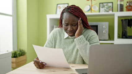 Canvas Print - African woman with braided hair reading document suffering for headache at dinning room