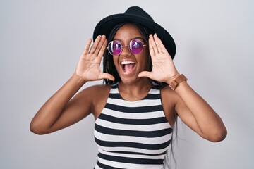 Poster - Young african american with braids wearing hat and sunglasses smiling cheerful playing peek a boo with hands showing face. surprised and exited