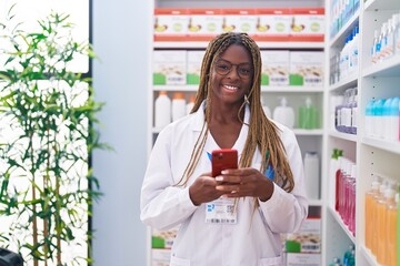 Wall Mural - African american woman pharmacist using smartphone working at pharmacy