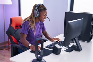 Sticker - African american woman streamer playing video game using computer at gaming room