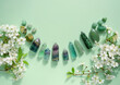 Crystal towers minerals set and white flowers on green abstract background. gemstones for Healing Crystal Ritual, Esoteric spiritual practice. wiccan magic, witchcraft. flat lay. copy space