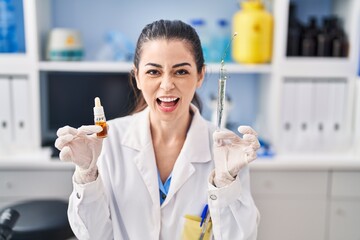 Canvas Print - Young woman doing weed oil extraction at laboratory angry and mad screaming frustrated and furious, shouting with anger. rage and aggressive concept.