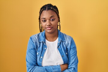 Sticker - African american woman with braids standing over yellow background looking sleepy and tired, exhausted for fatigue and hangover, lazy eyes in the morning.