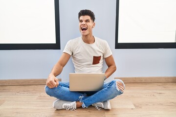 Sticker - Young hispanic man using laptop at home angry and mad screaming frustrated and furious, shouting with anger. rage and aggressive concept.