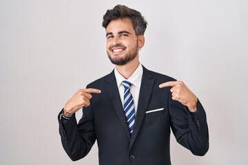 Poster - Young hispanic man with tattoos wearing business suit and tie looking confident with smile on face, pointing oneself with fingers proud and happy.