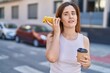 © Krakenimages.com - Young woman listening audio message by smartphone drinking coffee at street