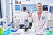 © Krakenimages.com - Young man working at scientist laboratory smiling with an idea or question pointing finger with happy face, number one