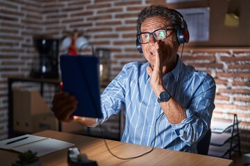 Sticker - Middle age hispanic man using touchpad sitting on the table at night hand on mouth telling secret rumor, whispering malicious talk conversation