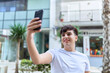 © Krakenimages.com - Non binary man smiling confident making selfie by the smartphone at street