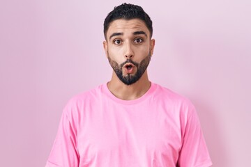 Canvas Print - Hispanic young man standing over pink background afraid and shocked with surprise and amazed expression, fear and excited face.