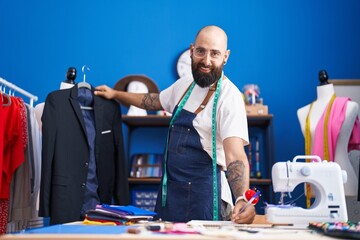 Poster - Young bald man tailor smiling confident holding jacket writing on notebook at clothing factory